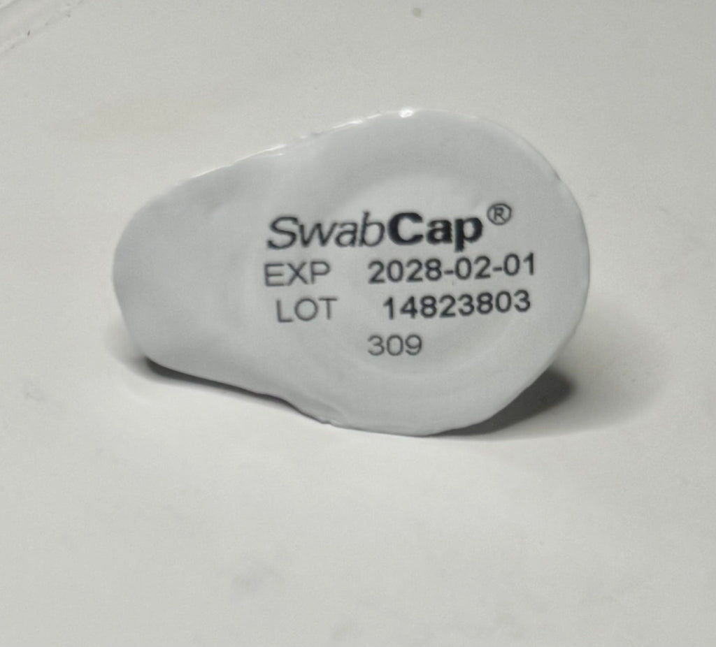 ICU Medical SwabCap single unit showing brand name, expiry 2028-02-01, lot 14823803